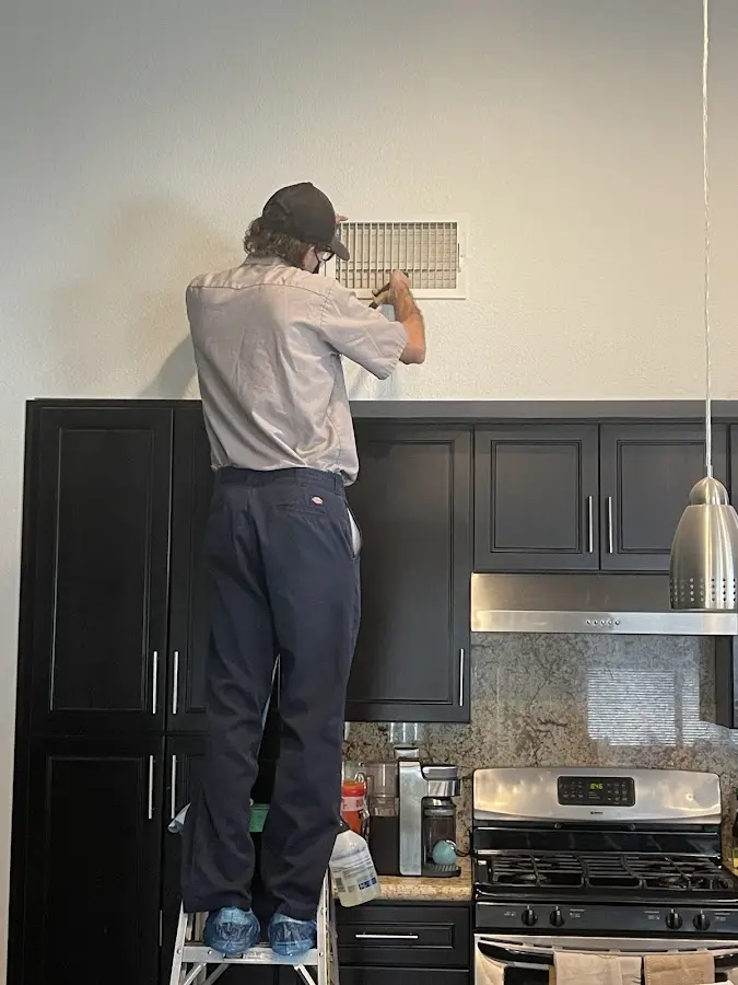 Technician inspecting an air vent during HVAC service in Upper Uwchlan